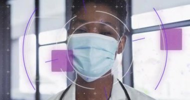 Yüz maskesi takmış Afro-Amerikan kadın doktor üzerinde veri işleme animasyonu. Küresel tıp, bilgisayar ve veri işleme kavramı dijital olarak oluşturulmuş video.