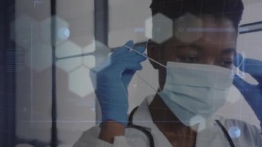Yüz maskesi takmış Afro-Amerikan kadın doktor üzerinde veri işleme animasyonu. Küresel tıp, bilgisayar ve veri işleme kavramı dijital olarak oluşturulmuş video.
