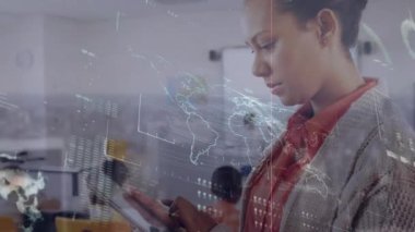 Tablet kullanan iki ırklı iş kadınının dünya haritası ve veri işleme animasyonu. Küresel iş, finans, hesaplama ve veri işleme kavramı dijital olarak oluşturulmuş video.