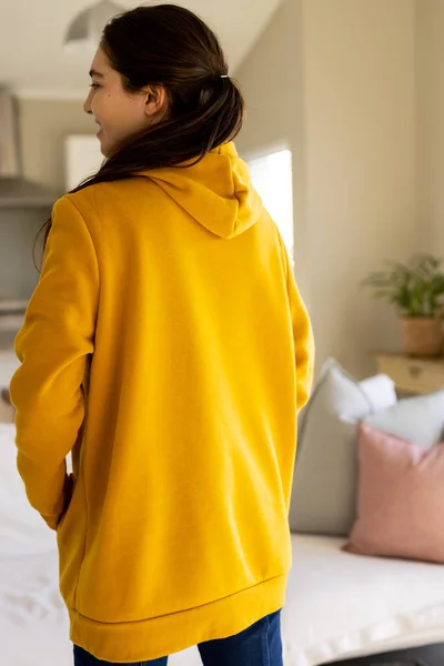 Biracial woman wearing yellow sweatshirt with copy space in living room. Fashion, design, color and clothes concept.