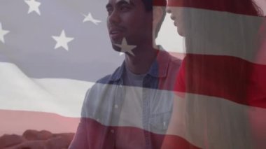 Sahildeki çeşitli çiftler üzerinde ABD bayrağının canlandırılması. Amerikan vatanseverliği ve çeşitlilik kavramı dijital olarak oluşturulmuş video.