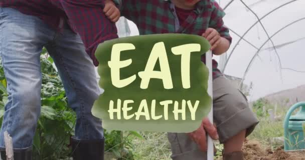 彼の息子に農業を教える白人男性農家の上に健康的なテキストバナーを食べるのアニメーション ビーガン オーガニック ヘルシーなフードコンセプト — ストック動画
