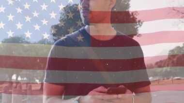 Amerikan bayrağının animasyonu, akıllı telefon kullanan iki ırklı bir adam üzerinde. Amerikan vatanseverliği ve çeşitlilik kavramı dijital olarak oluşturulmuş video.