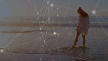 Kumsalda suda yürüyen beyaz kadın üzerindeki bağlantı ağının animasyonu. Küresel spor ve dijital arayüz kavramı dijital olarak oluşturulmuş video.