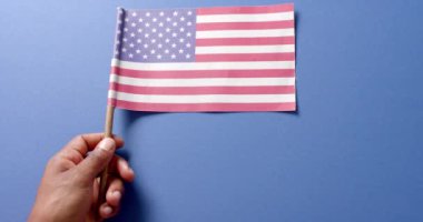 Mavi arka planda ABD bayrağını tutan el sıkışın. Amerikan vatanseverliği, bağımsızlık günü ve ulusal bayraklar.
