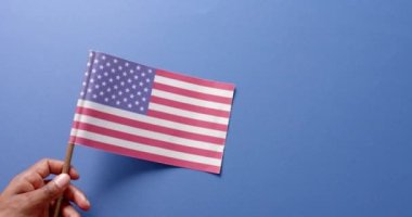 Mavi arka planda ABD bayrağını tutan el sıkışın. Amerikan vatanseverliği, bağımsızlık günü ve ulusal bayraklar.