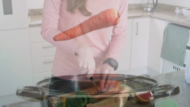 Animación Zanahorias Cayendo Olla Sobre Mujer Caucásica Picando Verduras Cocina — Vídeo de stock
