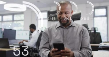Ofiste akıllı telefon kullanan Afro-Amerikan iş adamının veri işleme animasyonu. Küresel ağlar, işletmeler, finansmanlar, hesaplama ve veri işleme kavramı dijital olarak oluşturuldu.