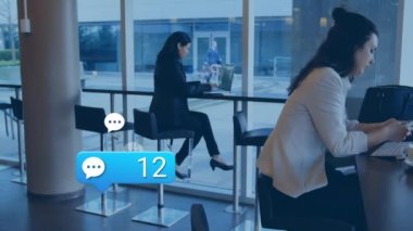 Kafe 'de akıllı telefon kullanan iki beyaz iş kadını üzerinde yüzen mesaj simgelerinin animasyonu. Sosyal medya ağı ve iş teknolojisi kavramı