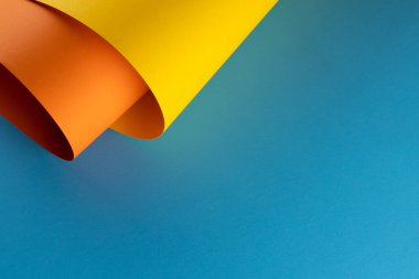 Mavi arkaplandaki sarı ve turuncu kağıtların fotokopi alanlarını kapatın. Renk, doku ve malzeme.