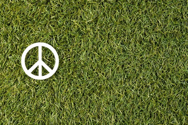 High angle view of white peace sign with copy space on grass background. Peace and anti war movement concept.