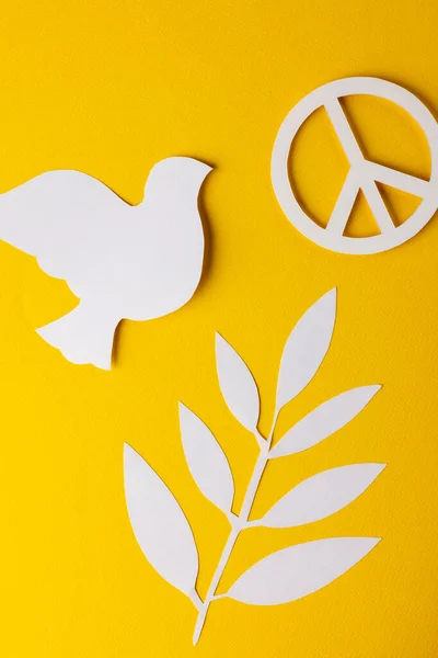 黄色の背景にコピースペースと白の平和記号 白い鳩と葉の高い角度ビュー 平和と反戦運動の概念 — ストック写真