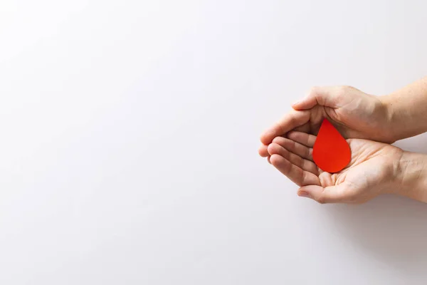 stock image Hands of caucasian woman cupping blood drop, on white background with copy space. Blood donation, medicine and healthcare.