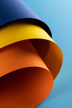 Mavi arka planda lacivert, sarı ve turuncu kağıtları kapatın. Renk, doku ve malzeme.