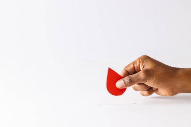 Kan damlasını yukarda tutan melez bir adamın eli beyaz arka planda fotokopi alanı ile birlikte. Kan bağışı, kan bankası, ilaç ve sağlık hizmetleri.