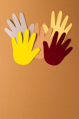 Kağıt çok renkli ellerden kesilmiş ve kahverengi arka planda fotokopi alanı var. İnsani yardım, insanlar, yardım ve insan kavramı.