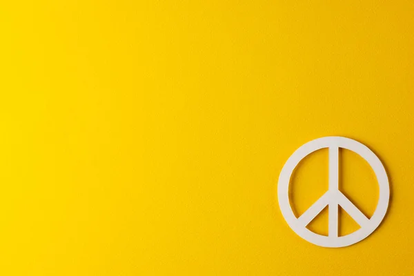 白色和平标志的高角度视图 黄色背景上有复制空间 和平与反战运动概念 — 图库照片