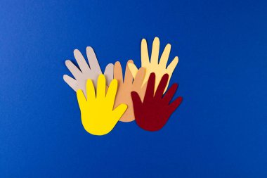 Çok renkli ellerden kesilmiş kağıtları kapatın ve mavi arkaplanda kopya alanı olsun. İnsani yardım, insanlar, yardım ve insan kavramı.