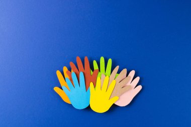 Çok renkli ellerden kesilmiş kağıtları kapatın ve mavi arkaplanda kopya alanı olsun. İnsani yardım, insanlar, yardım ve insan kavramı.
