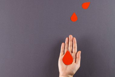 Beyaz bir kadının elinde kan damlası var. Arka planda kan damlaları var. Kopya uzayı. Kan bağışı, ilaç ve sağlık hizmetleri.