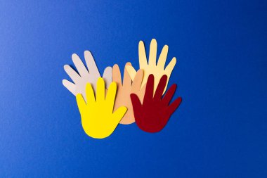 Çok renkli ellerden kesilmiş kağıtları kapatın ve mavi arkaplanda kopya alanı olsun. İnsani yardım, insanlar, yardım ve insan kavramı.