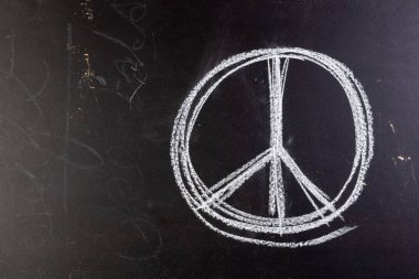 Siyah tahtada beyaz tebeşirle barış işaretini kapatın. Barış ve savaş karşıtı hareket kavramı.