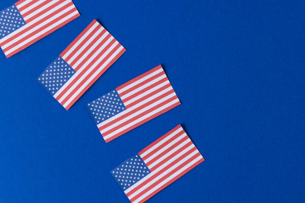 High angle view of four flags of united states of america with copy space on blue background. American patriotism, independence day and tradition concept.