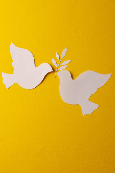 Закройте двумя белыми голубями лист и скопируйте пространство на желтом фоне. Концепция мирного и антивоенного движения.