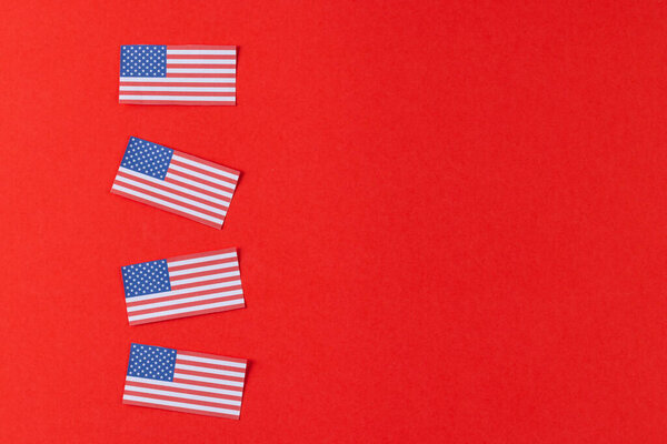 High angle view of four flags of united states of america with copy space on red background. American patriotism, independence day and tradition concept.