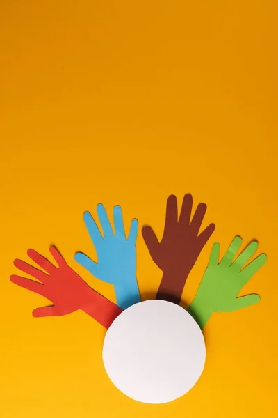 オレンジ色の背景にコピースペースのある複数の色の手と白い円から切り取られた紙 人道支援 人間の概念 — ストック写真