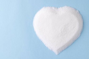 Mavi arka planda kalp şeklinde ve kopya alanı olan şeker. Diyet, kan şekeri, diyabet ve kalp sağlığı farkındalığı.