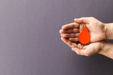 Beyaz kadının elleri, arka planda kan damlalarını kopyalanmış şekilde tutuyor. Kan bağışı, ilaç ve sağlık hizmetleri.