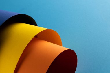 Lacivert, sarı ve turuncu kağıtları mavi arkaplanda fotokopi alanı ile kapatın. Renk, doku ve malzeme.