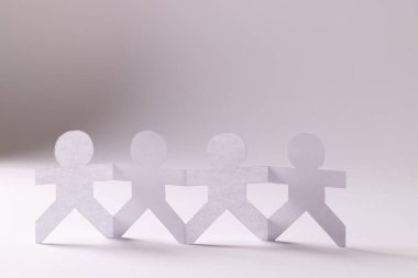 Beyaz arka planda fotokopi alanıyla el ele tutuşan dört kağıt kesimini kapatın. İnsani yardım, insanlar, yardım ve insan kavramı.