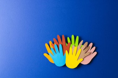 Çok renkli ellerden kesilmiş kağıtları kapatın ve mavi arkaplanda kopya alanı olsun. İnsani yardım, insanlar, yardım ve insan kavramı.