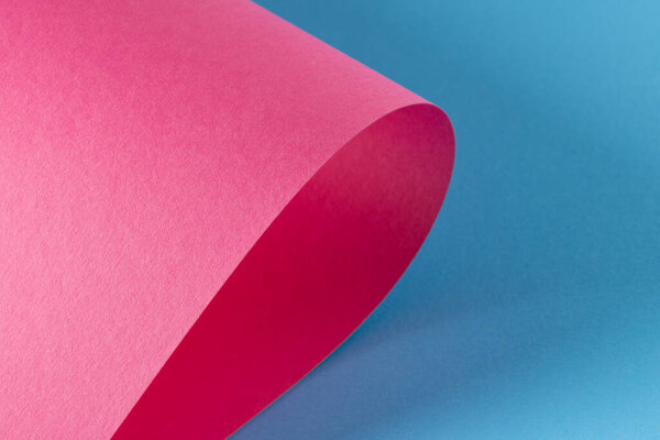 Close up of pink paper on blue background with copy space. Colour, texture and material.