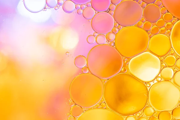 Macro close up of water bubbles with copy space over pink and yellow background. Macro, colour, water, shape and pattern concept.