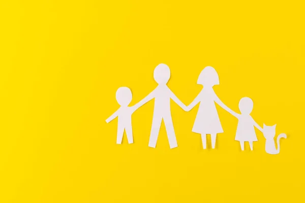 White paper cut out of family with two children and ca and copy space on yellow background. Humanitarian aid, people, help and human concept.