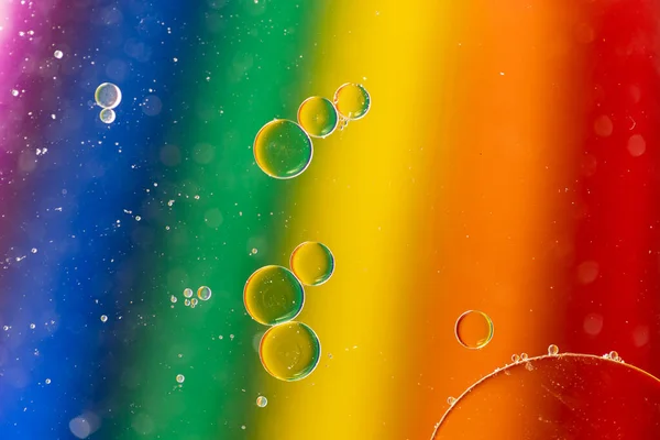 Macro close up of water bubbles with copy space on rainbow background. Macro, colour, water, shape and pattern concept.