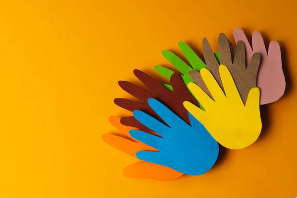Großaufnahme Von Papier Aus Mehrfarbigen Händen Mit Kopierraum Auf Orangefarbenem — Stockfoto