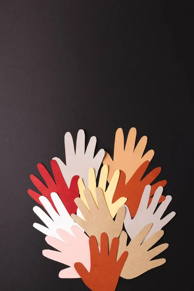 Paper cut out of multi coloured hands with copy space on black background. Humanitarian aid, people, help and human concept.