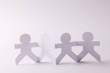 Beyaz arka planda fotokopi alanıyla el ele tutuşan dört kağıt kesimini kapatın. İnsani yardım, insanlar, yardım ve insan kavramı.