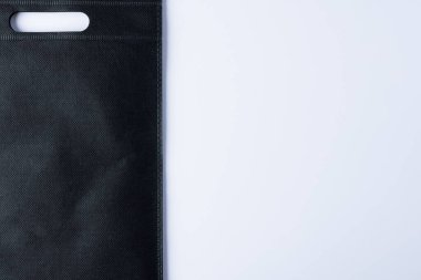 Beyaz arka planda fotokopi alanı olan siyah çantanın yüksek açılı görüntüsü. Çantalar ve moda konsepti.