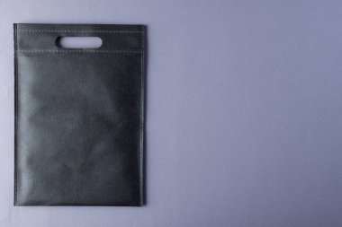 Gri arkaplanda fotokopi alanı olan siyah çantanın yüksek açılı görüntüsü. Çantalar ve moda konsepti.