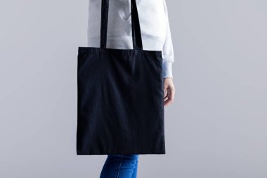Beyaz kadın elinde gri arka planda fotokopi alanı olan siyah bir çanta tutuyor. Çantalar ve moda konsepti.
