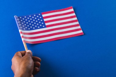 Amerika Birleşik Devletleri bayrağını elinde tutan melez bir adamın eli. Amerikan vatanseverliği, bağımsızlık günü ve gelenek kavramı.