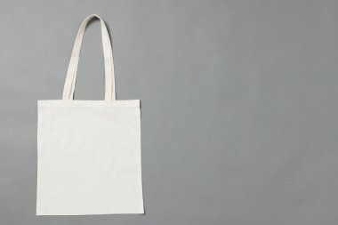 Gri arkaplanda kopya alanı olan beyaz bez çantanın yüksek açılı görüntüsü. Çantalar ve moda konsepti.