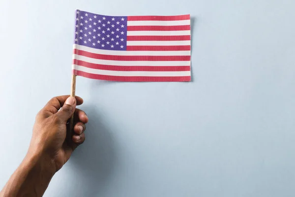 Hand of biracial man holding flag of united states of america with copy space. American patriotism, independence day and tradition concept.