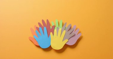 Turuncu arkaplanda fotokopi alanı olan renkli kağıtlardan yapılmış elleri birbirine yakın tutun. Topluluk, küresel, insanlar ve sanat.