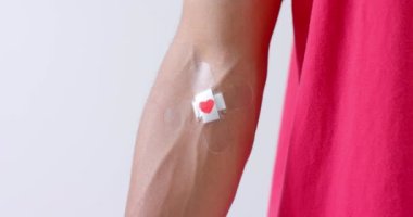 Koluna alçı yapıştıran, beyaz arka planda, ağır çekimde, melez bir adamın koluna yaklaş. Kan bağışı, ilaç ve sağlık hizmetleri.